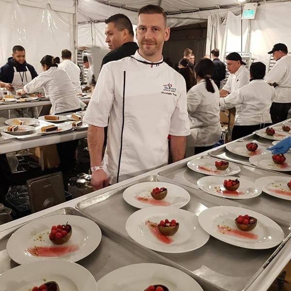 Chef Christophe Rull of Little France Coffee & Bakery stands among staff preparing raspberry desserts.