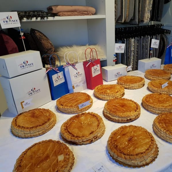 A table filled with golden-brown Galette des Rois pastries and Little France branded boxes and bags.
