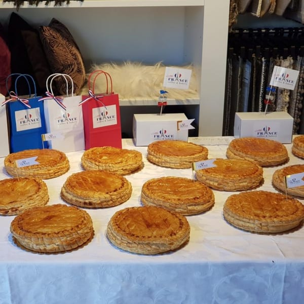 Golden-brown Galette des Rois pastries with Little France Coffee & Bakery branding on a white tablecloth.