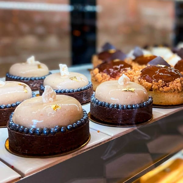 Rows of elegant French pastries with glossy tops and decorative borders on display at Little France Coffee & Bakery.