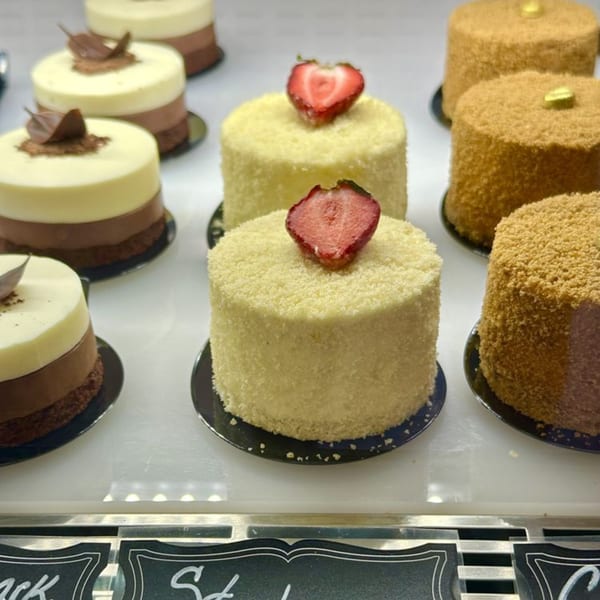 Assortment of small cakes, including layered chocolate and strawberry-topped white cakes, displayed at Little France.